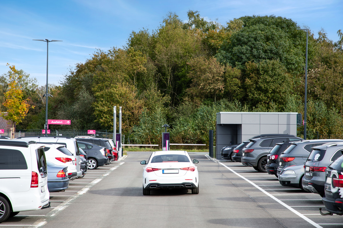 Hvid bil kører gennem en bred, asfalteret parkeringsvej på Easy Airport Parking parkeringspladsen ved Münster/Osnabrück lufthavn (FMO)
