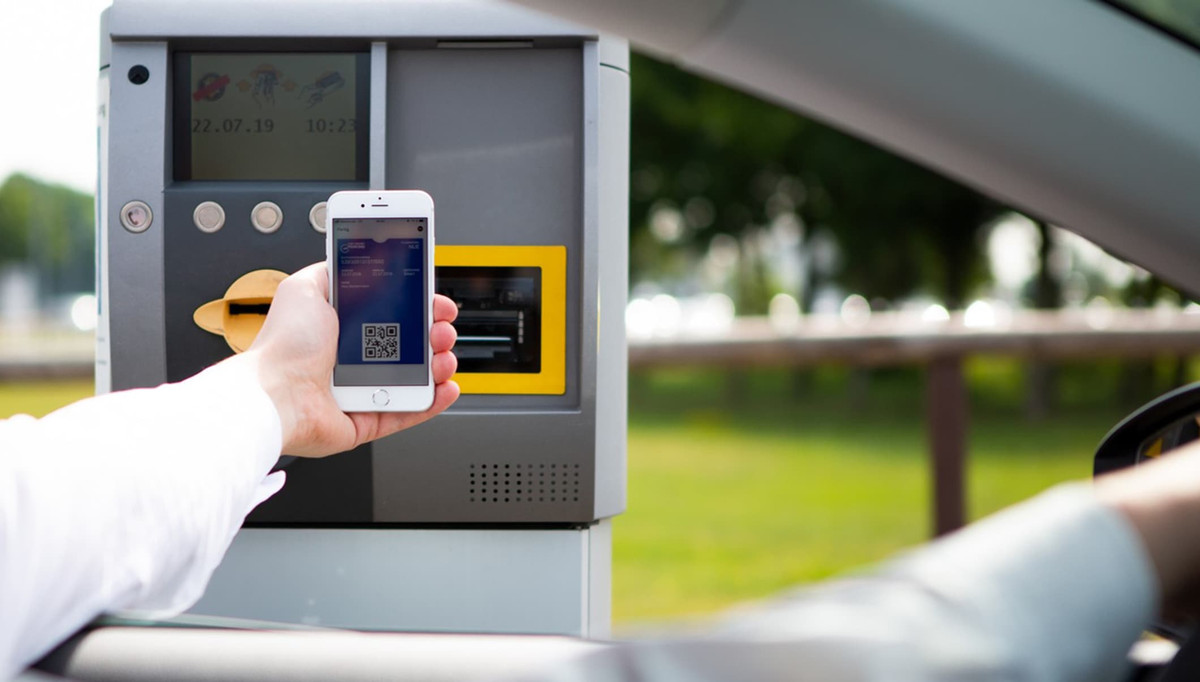 Ein Autofahrer scannt QR-Code mit dem Handy am Einfahrtsterminal des Parkplatzes von Easy Airport Parking am Flughafen Frankfurt-Hahn (HHN)