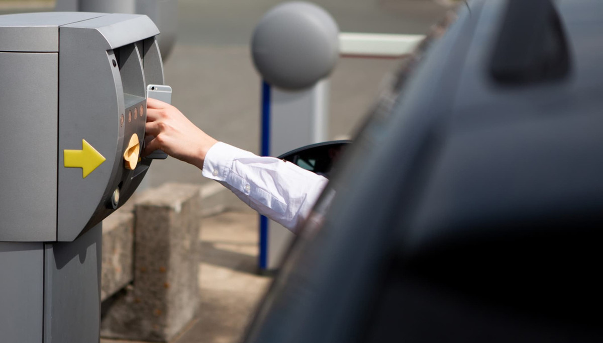 Fahrer checkt mit dem Smartphone an der Einfahrt des Parkplatzes von Easy Airport Parking am Flughafen Frankfurt-Hahn (HHN) ein
