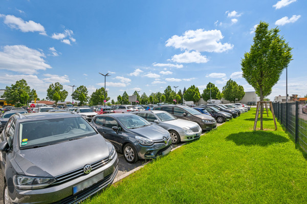 Verzorgde groenstroken aan de rand van de met auto's gevulde parkeerplaats van Easy Airport Parking op luchthaven Stuttgart (STR)
