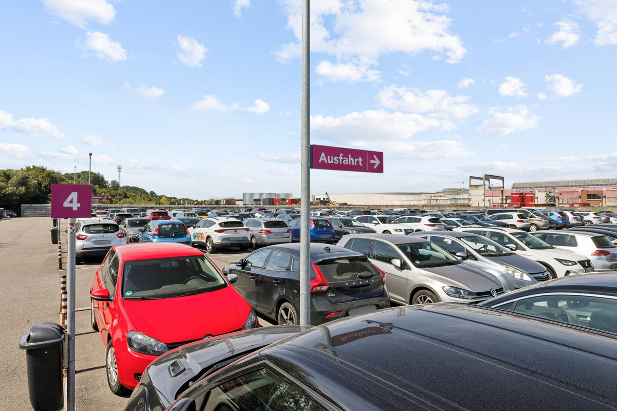 Parkende Autos und Hinweisschilder auf dem Easy Airport Parking Parkplatz am Flughafen Weeze (NRN)